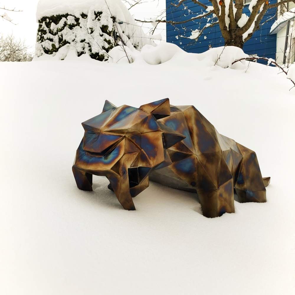 Small saber-toothed tiger sculpture in burnished welded steel, placed in snowy surroundings